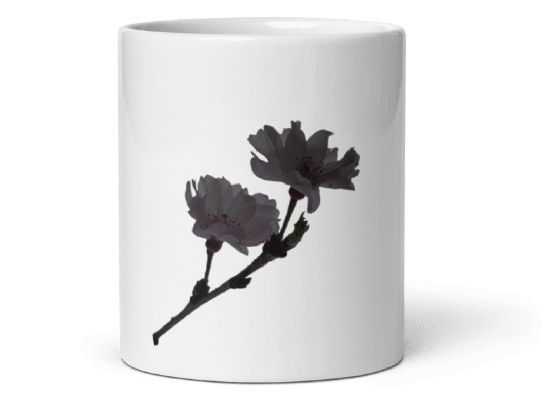 A white ceramic mug featuring a printed graphic of two dark gray blossoms on a branch, set against a plain white background.