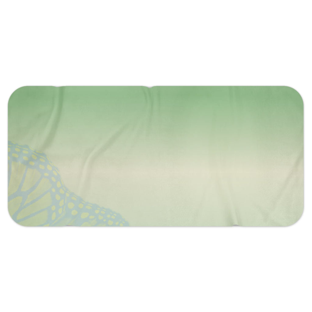 A rectangular bath mat with rounded corners featuring a pastel gradient background of green, pink, and purple, decorated with butterfly wing patterns in the bottom corners.