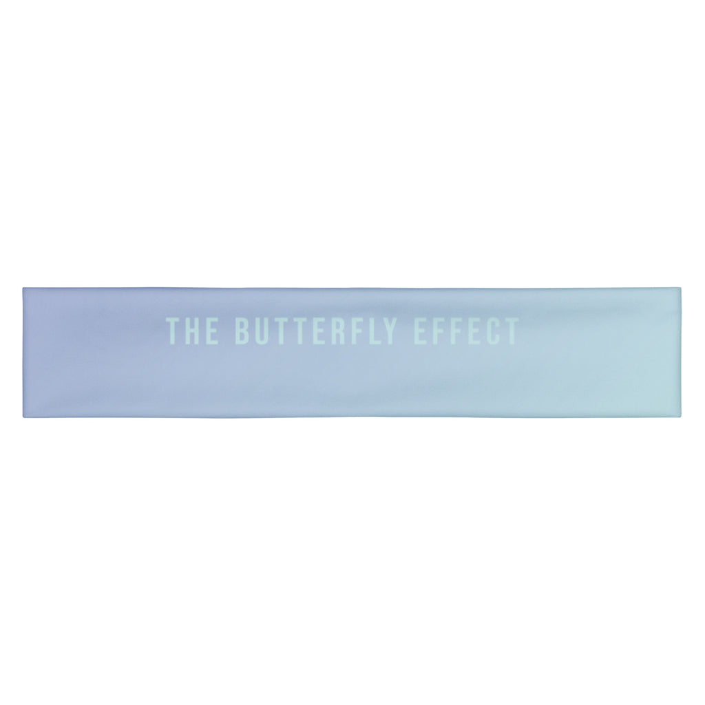A rectangular fabric bandana or scarf in a light blue to lavender-purple gradient, featuring the text 'THE BUTTERFLY EFFECT' printed in a matching pale blue tone across the center, set against a plain white background.