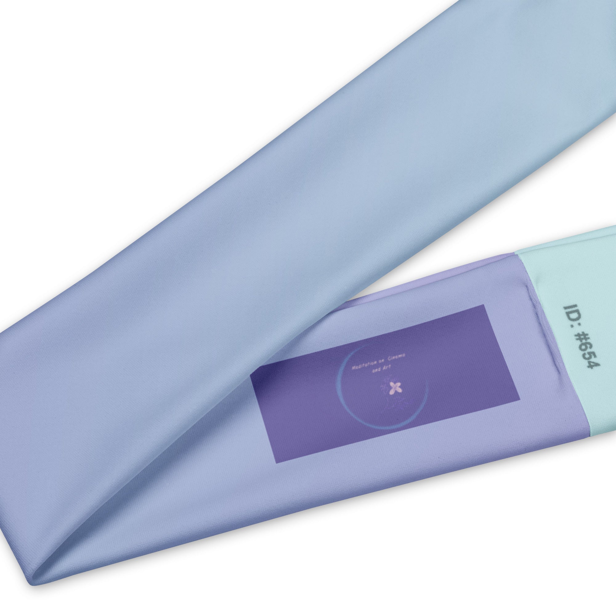 A folded light blue satin-like fabric item, likely a sheet or duvet cover, shown on a white background with a purple label and mint green edge detail.