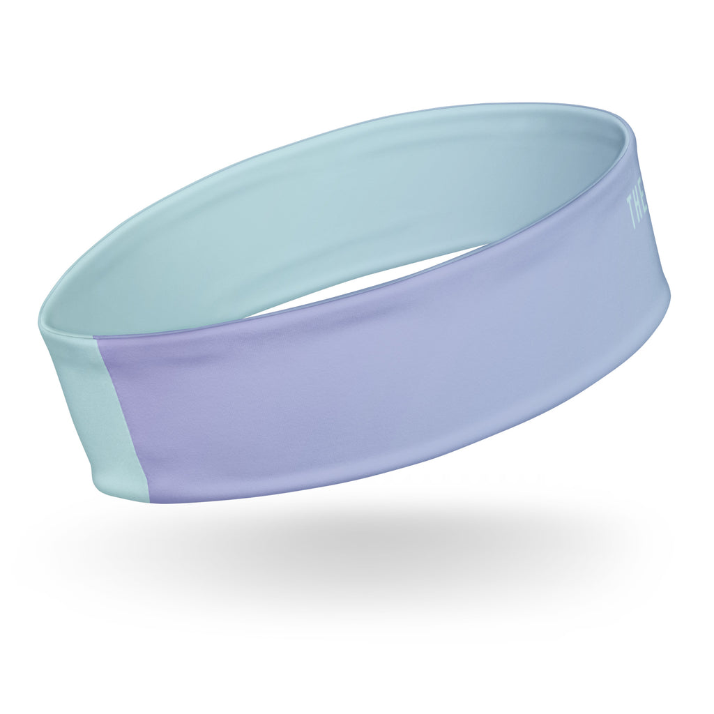 An athletic headband with a dual-tone design, featuring a lavender purple front band and a light mint green interior and side panel, shown floating on a white background with a soft shadow.