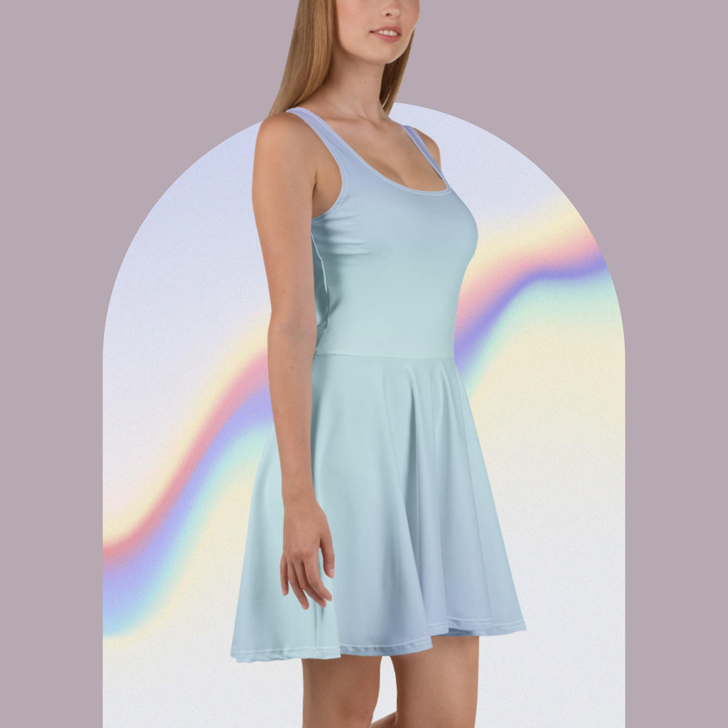 A woman wearing a sleeveless light blue scoop-neck skater dress, shown from the waist up against a pale lavender background with a soft rainbow arch graphic.