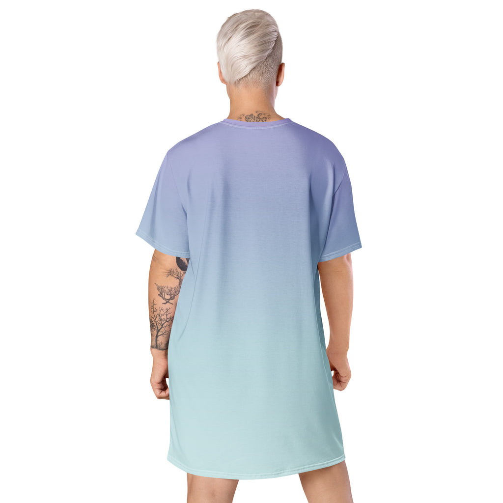 A model shown from the back wearing an oversized short-sleeve tunic dress with a smooth vertical gradient transitioning from lavender-blue at the top to pale mint green at the bottom, on a plain white background.