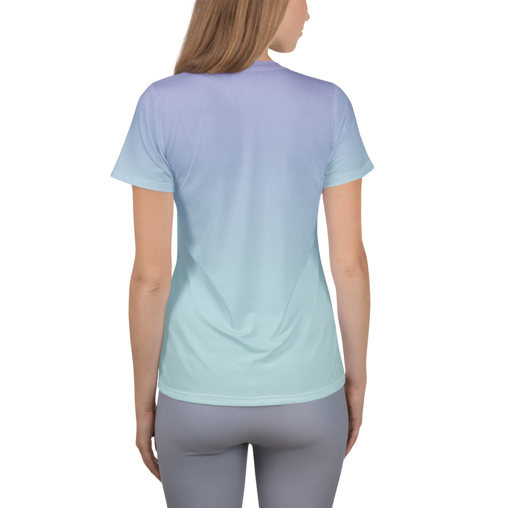 A woman viewed from the back wearing a short-sleeve athletic T-shirt with a smooth vertical gradient transitioning from light lavender at the shoulders to pale aqua at the hem, paired with gray leggings on a white studio background.