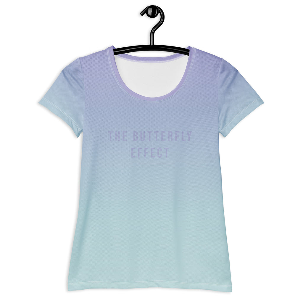 A short-sleeve scoop-neck t-shirt hanging on a black hanger against a white background, featuring a smooth vertical gradient from light lavender purple at the top to pale icy blue at the bottom, with the text 'THE BUTTERFLY EFFECT' printed in a matching light purple font on the chest.