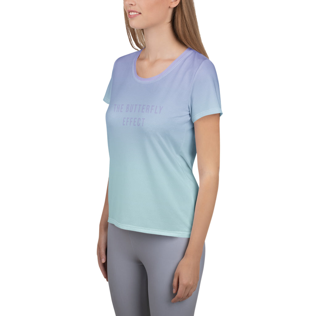 A woman wearing a short-sleeve athletic t-shirt with a smooth color gradient transitioning from light lavender purple to mint green, paired with gray leggings, shown against a plain white background.