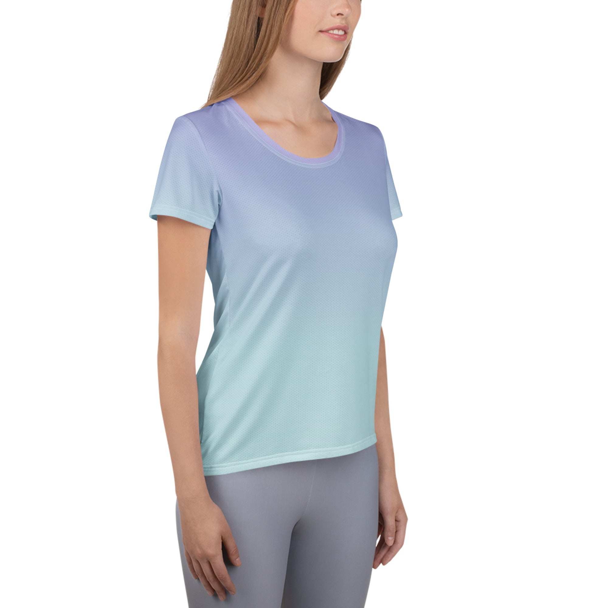 A woman wearing a short-sleeve athletic crewneck top with a smooth color gradient from light periwinkle blue at the shoulders to a soft mint green at the hem, paired with gray leggings, against a plain white background.