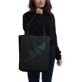 Person holding a black tote bag with text on a white background