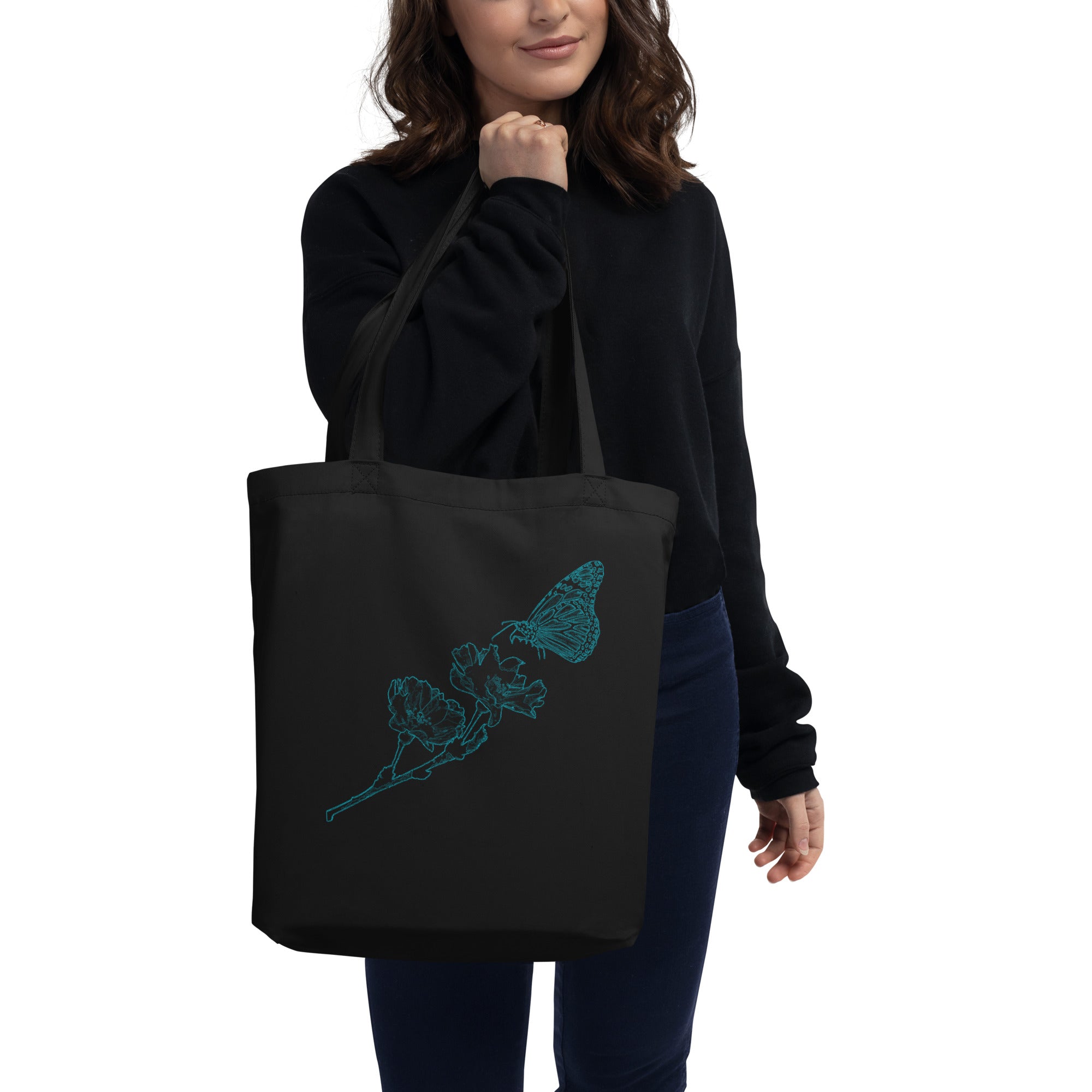 Person holding a black tote bag with text on a white background